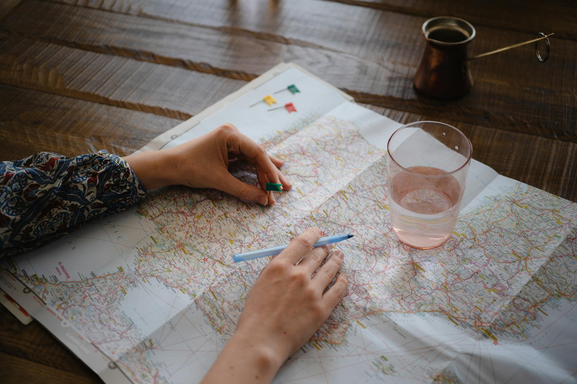 Kobieta planuje tani wyjazd, wbijając pinezkę w mapę na stole