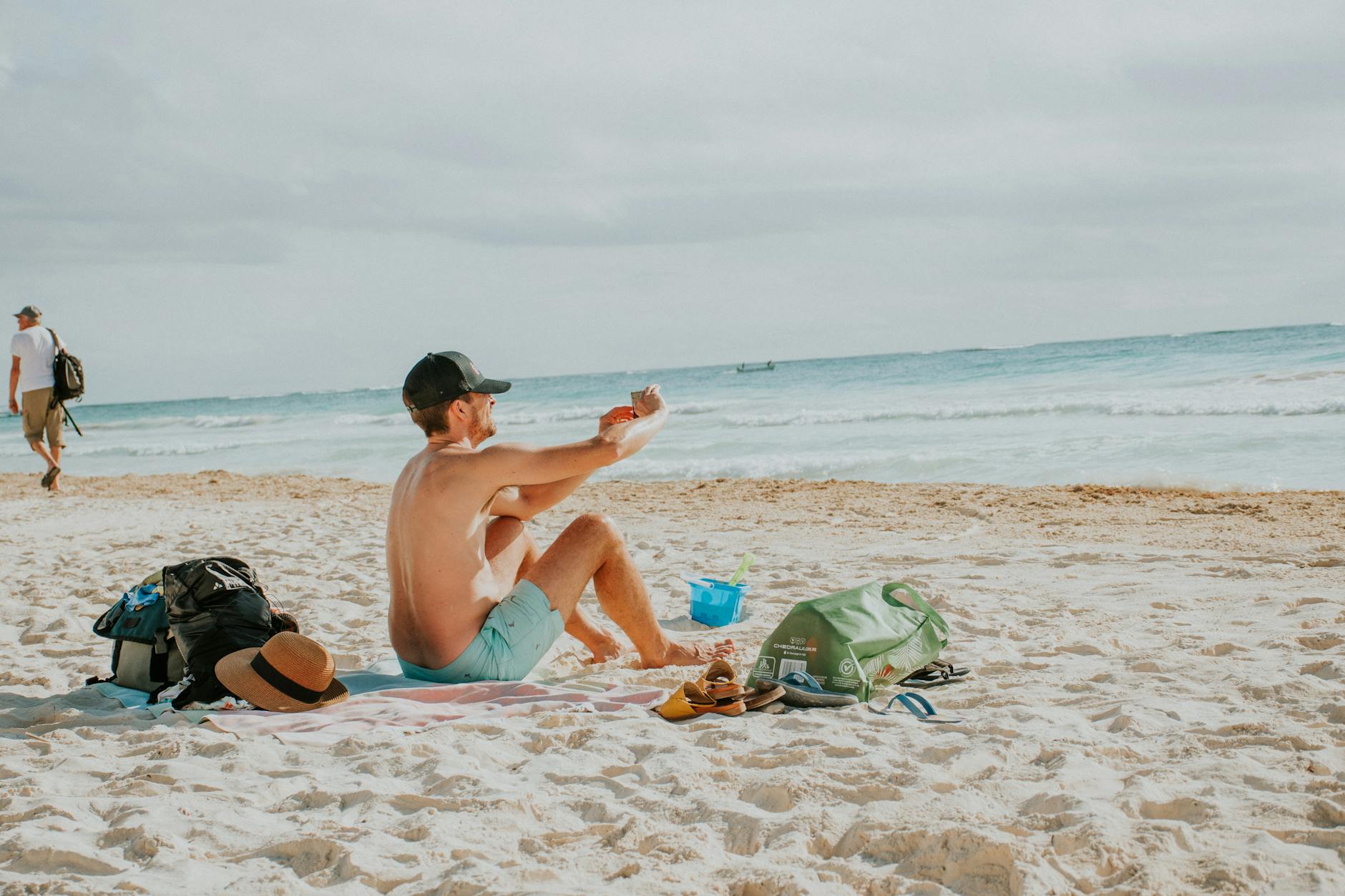Mężczyzna na piaszczystej plaży nakłada krem z filtrem nad morzem