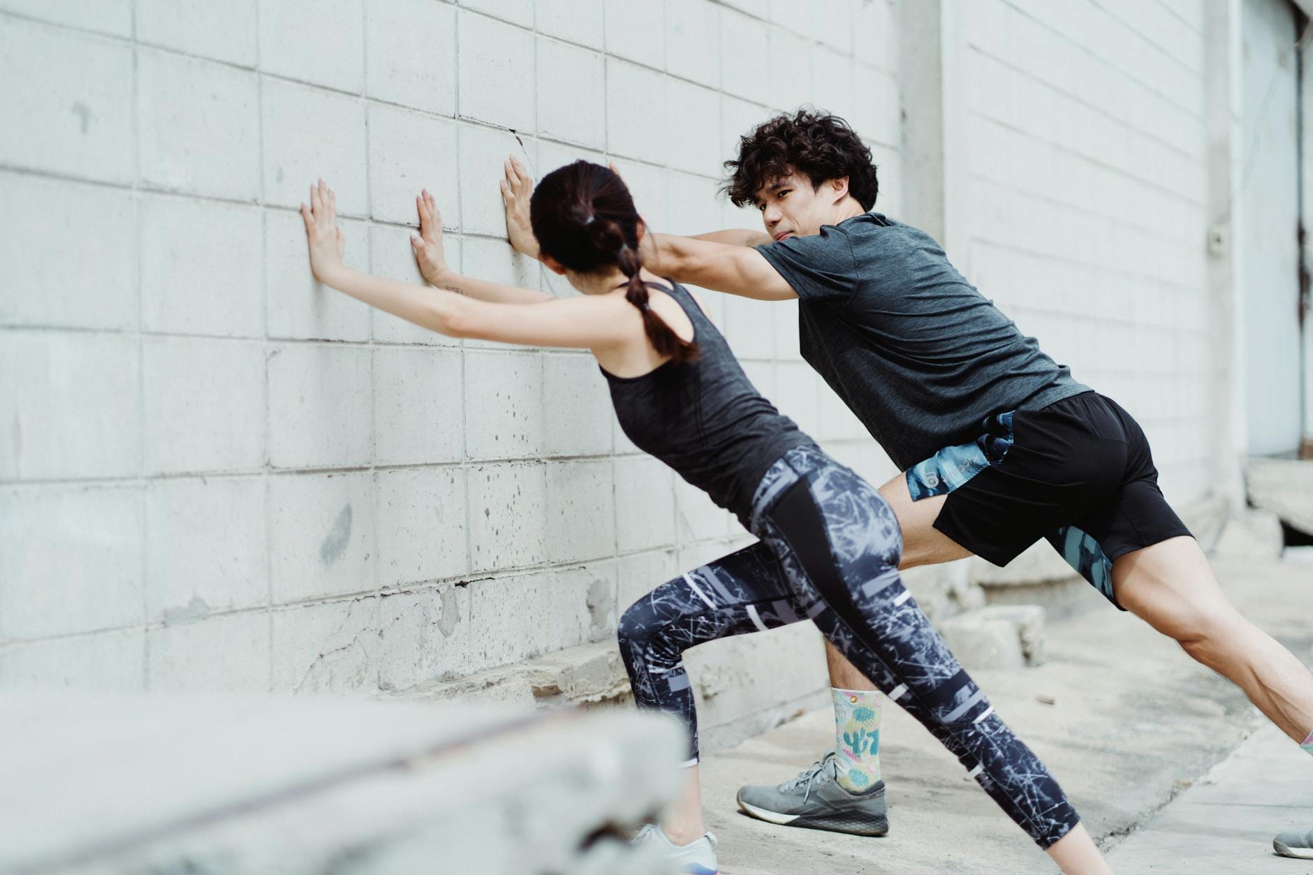 Para rozciąga się przy murze podczas treningu na świeżym powietrzu