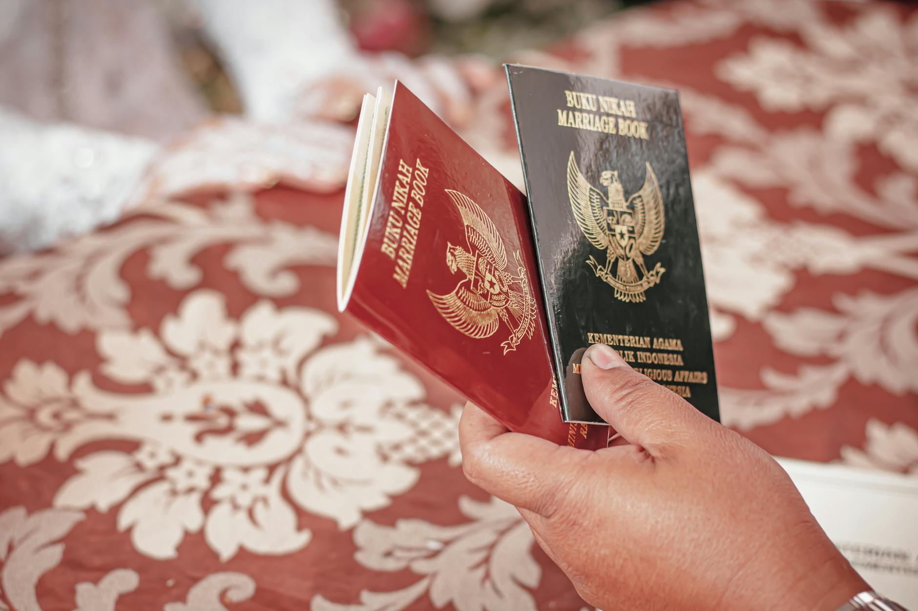 Podróż poślubna za granicą formalności dokumenty i zmiana nazwiska po ślubie Para trzyma indonezyjskie księgi małżeńskie podczas ceremonii ślubnej