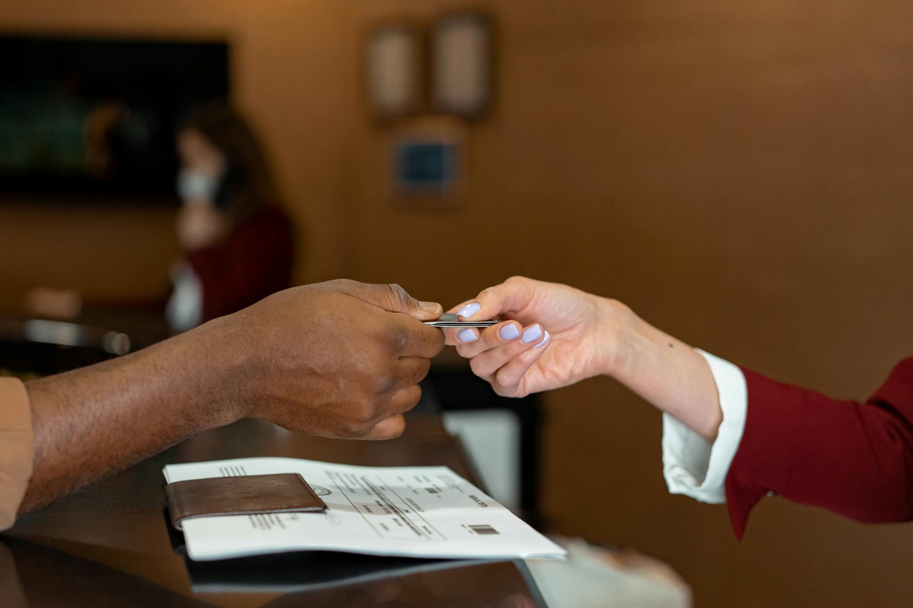 Recepcjonista hotelowy przyjmuje kartę płatniczą od gościa przy check-in