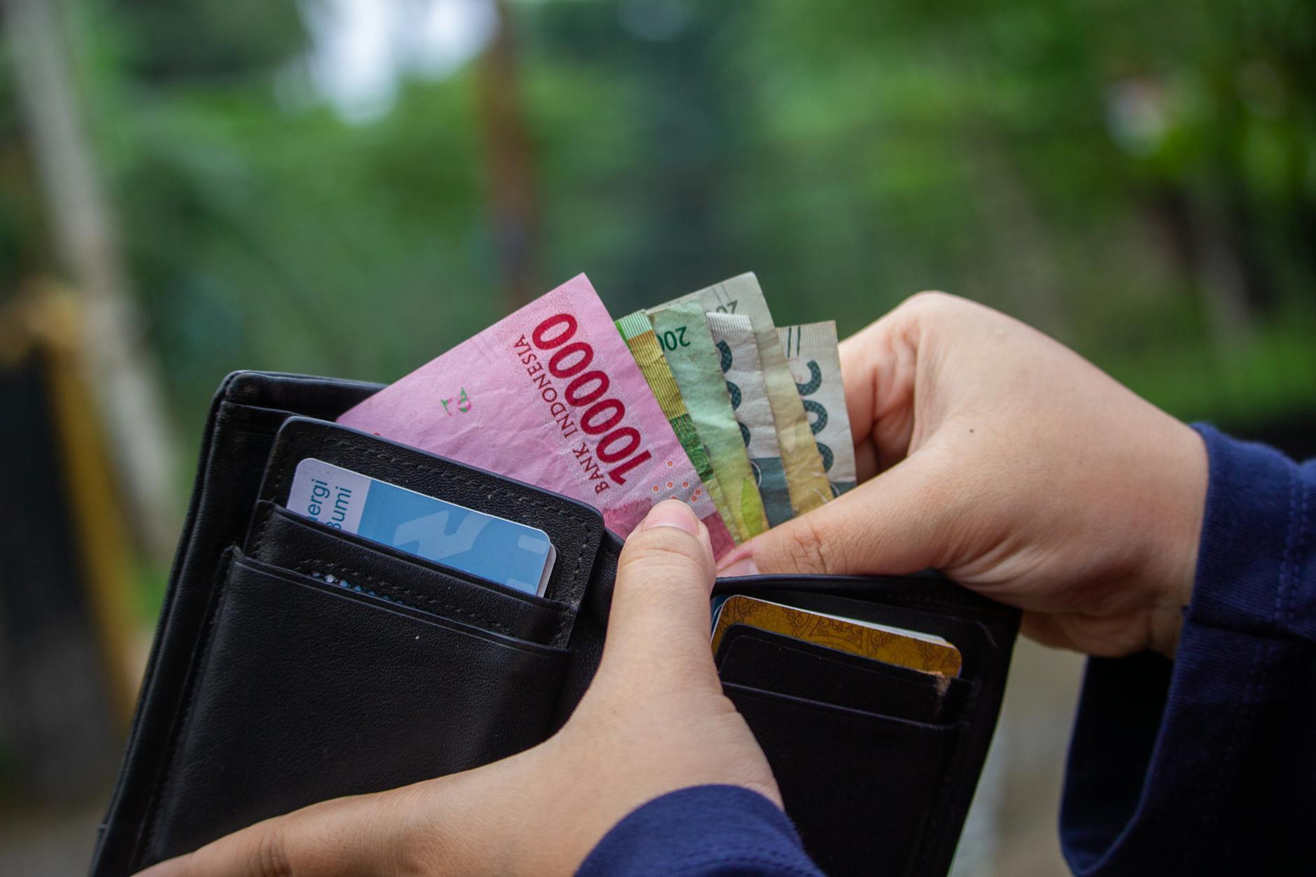 Ręka wyciąga banknoty rupii indonezyjskiej z portfela na zewnątrz
