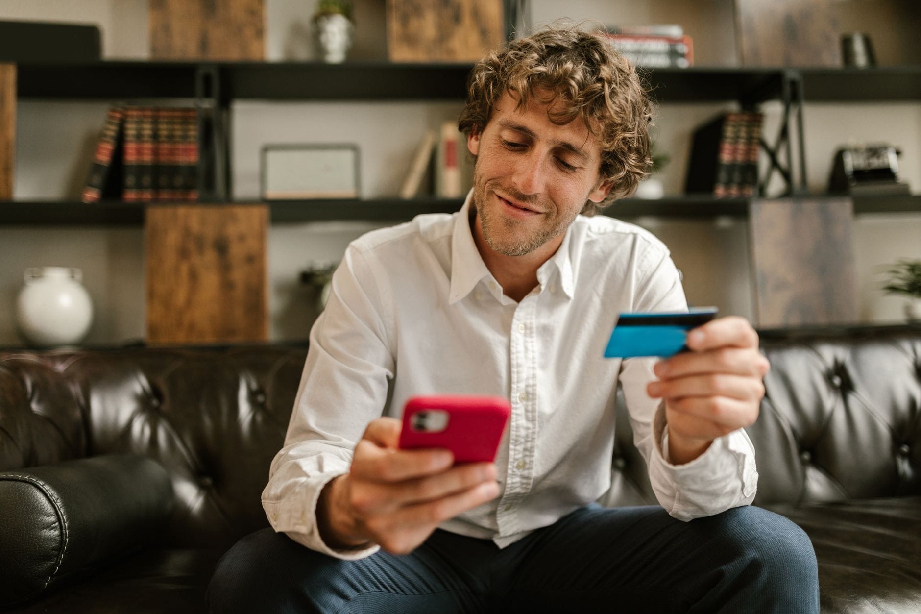 Mężczyzna trzymający smartfon i kartę kredytową podczas płatności online
